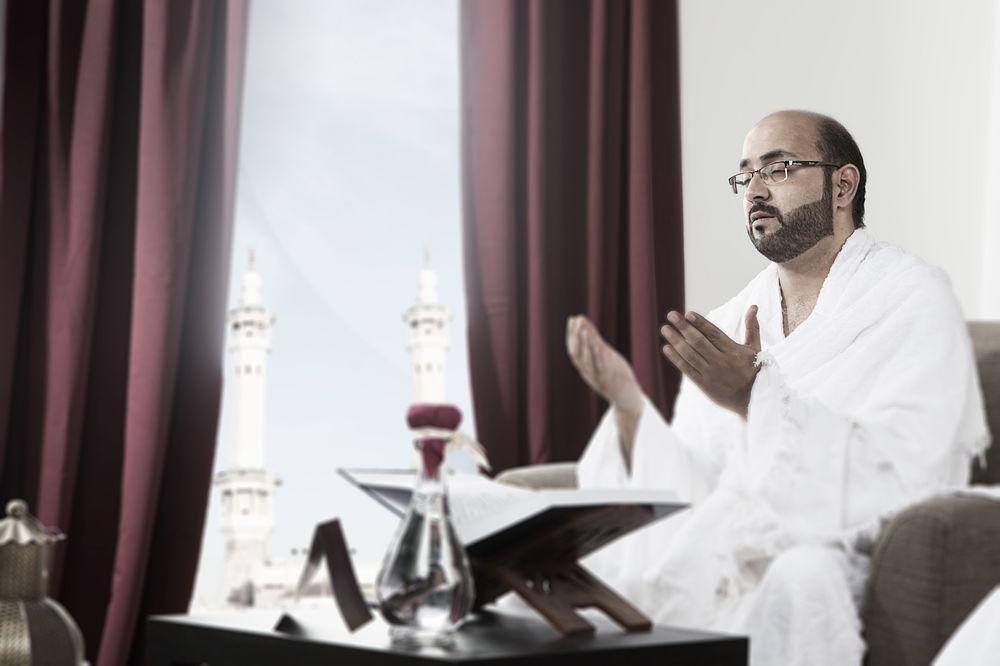 מכה Makarem Ajyad Makkah Hotel מראה חיצוני תמונה The photo depicts a man sitting in a room, wearing traditional white garments typically associated with the Hajj pilgrimage. He appears to be engaged in a prayer or spiritual practice, with his hands raised in a gesture of supplication. In the backgr