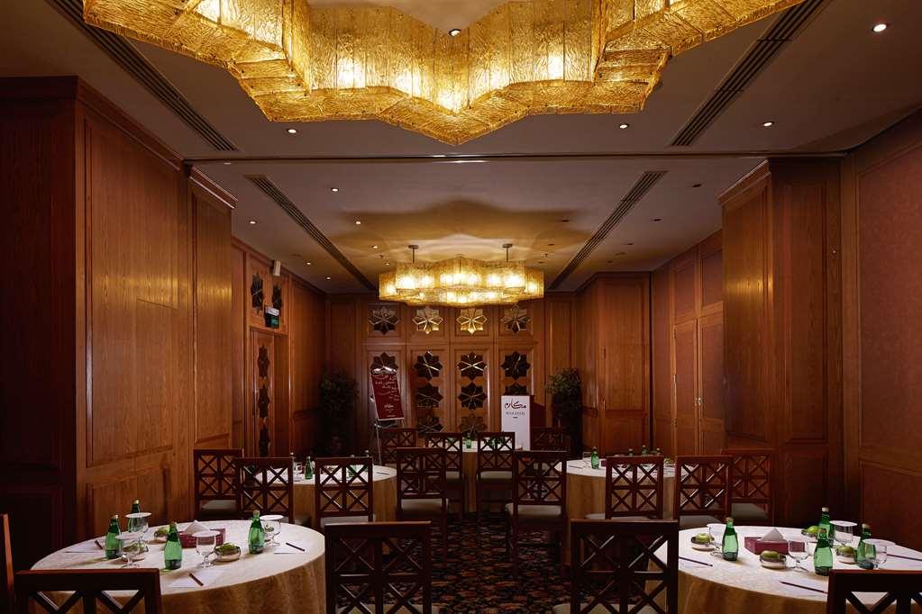 מכה Makarem Ajyad Makkah Hotel מתקנים תמונה The photo shows a well-decorated dining room with wooden paneling and elegant furnishings. There are round tables covered with tablecloths, and each table is arranged with glasses of water. The lighting is warm, provided by elaborate chandeliers on t