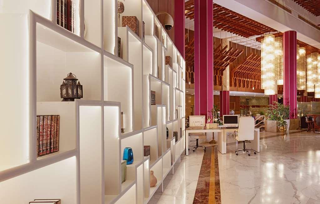 מכה Makarem Ajyad Makkah Hotel מראה פנימי תמונה The photo shows a modern interior space, likely a lobby or lounge area of a stylish hotel or building. There is a partition wall made up of white shelving units illuminated from within, displaying various decorative items, books, and vases. The desig