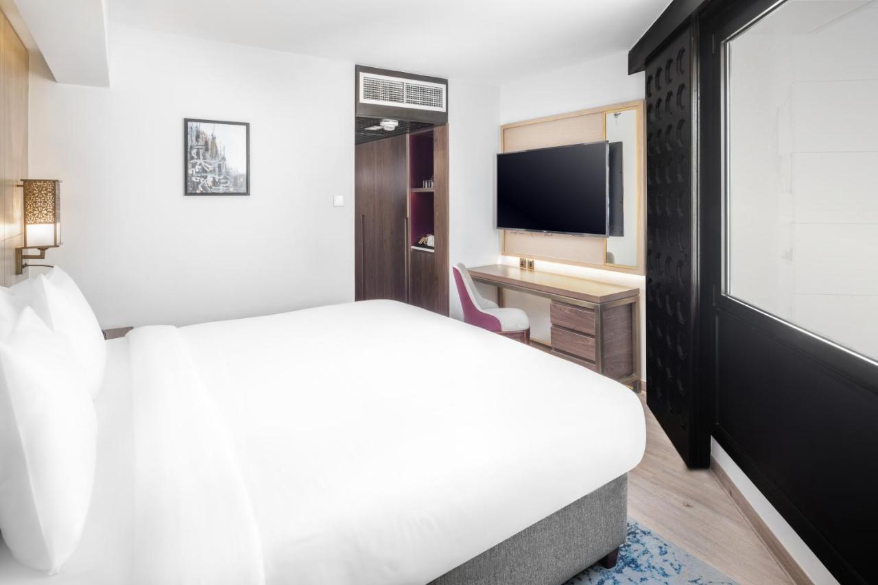 מכה Makarem Ajyad Makkah Hotel מראה חיצוני תמונה The photo shows a modern hotel room featuring a large bed with white linens at the forefront. In the background, there is a wall-mounted television across from a desk with a chair. A wardrobe or cabinet is located to the side, and there's a decorativ