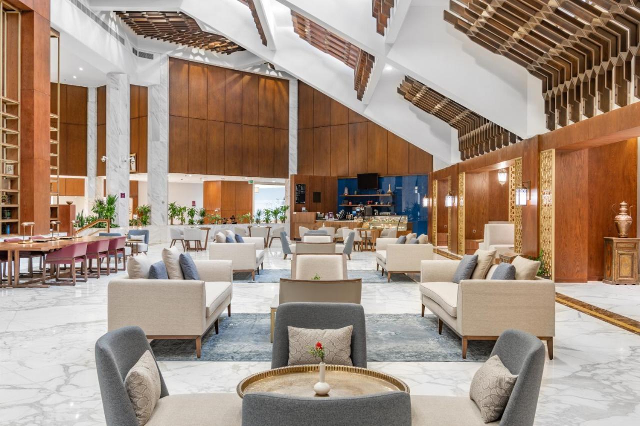 מכה Makarem Ajyad Makkah Hotel מראה חיצוני תמונה The photo depicts the interior of a modern and elegantly designed lobby or lounge area. It features a spacious layout with high ceilings, showcasing a combination of wooden elements and marble flooring. 

In the center, there are several seating arra
