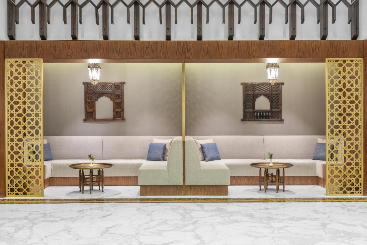 מכה Makarem Ajyad Makkah Hotel מראה חיצוני תמונה The photo depicts a modern, elegantly designed seating area. It features a pair of sofas with light-colored upholstery, accented by blue cushions. There are several small tables in front of the sofas, likely meant for drinks or decorative items. The 