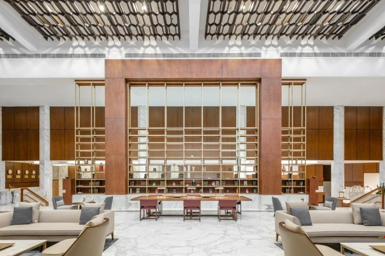 מכה Makarem Ajyad Makkah Hotel מראה חיצוני תמונה The photo shows a spacious interior of a modern lobby or lounge. The design features a large wooden structure with a grid-like pattern in the center, possibly serving as a decorative partition. The walls are adorned with brown wooden panels, and marb