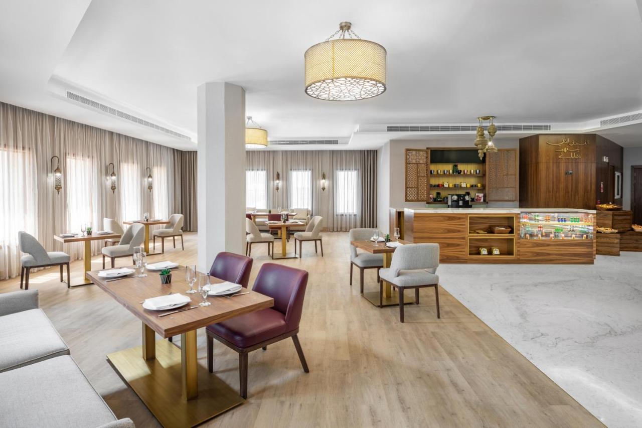 מכה Makarem Ajyad Makkah Hotel מראה חיצוני תמונה The photo depicts a modern and stylish restaurant interior. The space features a combination of wooden and upholstered furniture, with several dining tables arranged throughout. The tables are set with dishes and cutlery, indicating readiness for ser