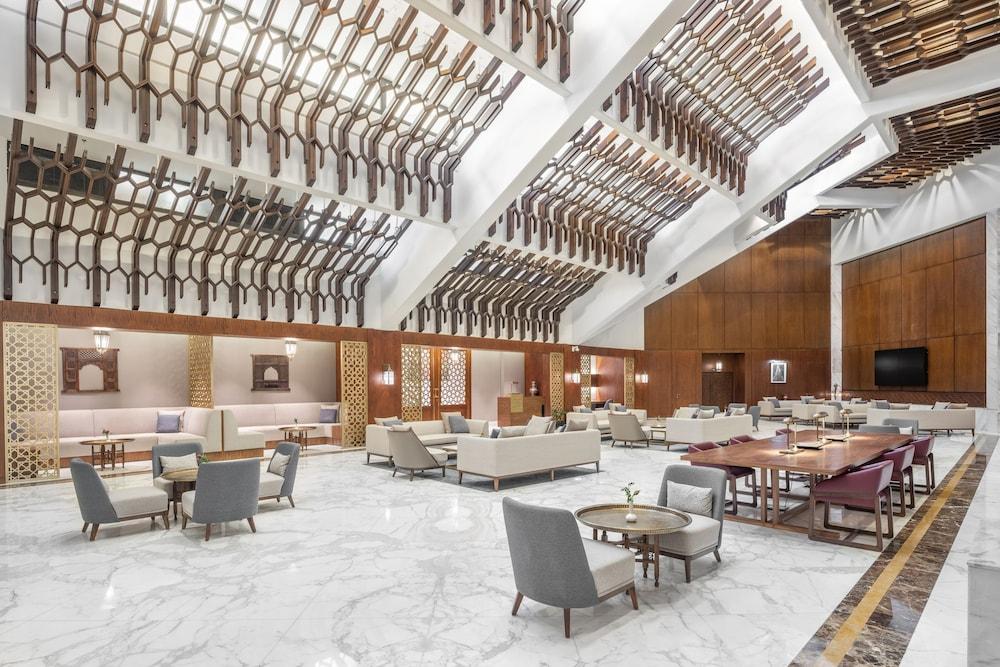 מכה Makarem Ajyad Makkah Hotel מראה חיצוני תמונה The photo shows a spacious and elegantly designed lobby area, likely within a hotel. The interior features high ceilings with a unique architectural design, showcasing wooden elements arranged in a geometric pattern. The flooring is a polished marble