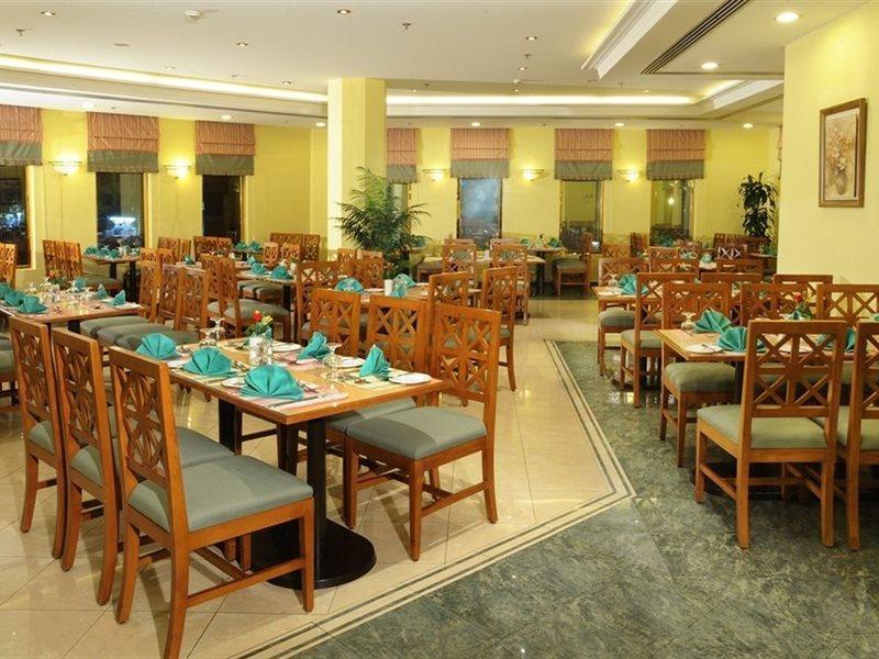 מכה Makarem Ajyad Makkah Hotel מראה חיצוני תמונה The photo shows an interior view of a restaurant. It features wooden tables and chairs arranged neatly throughout the space. Each table is set with turquoise napkins, contributing to the overall decor. The walls are painted a soft yellow, and there a