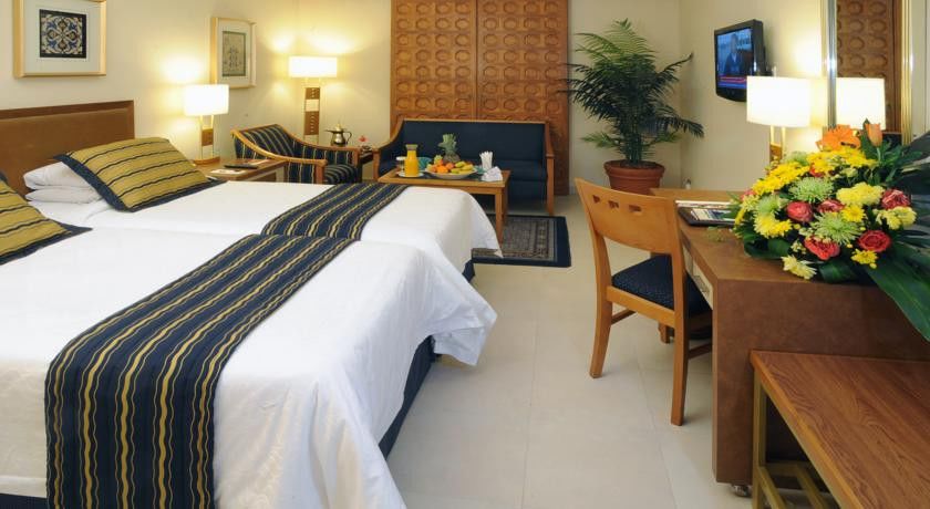 מכה Makarem Ajyad Makkah Hotel מראה חיצוני תמונה The image shows a hotel room featuring two beds with white linens and a decorative stripe along the edge. There is a seating area with two chairs and a small table, set with a breakfast spread that includes fruit and drinks. A small potted plant adds