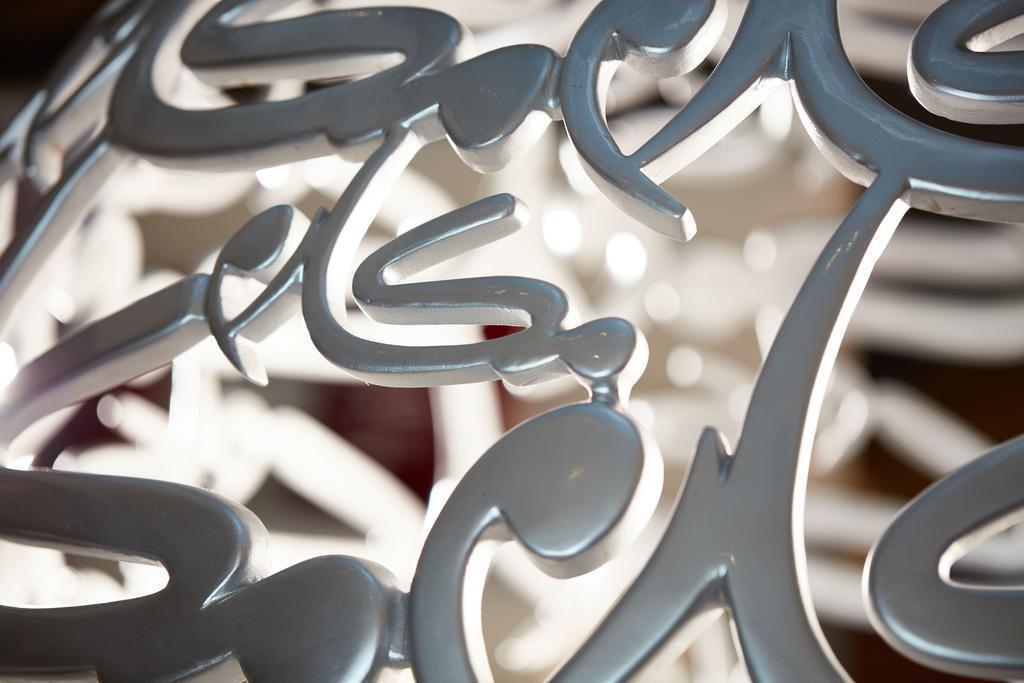 מכה Makarem Ajyad Makkah Hotel מראה חיצוני תמונה The photo shows a close-up of a white, artistic structure or piece of decor that features intricate, stylized lettering. The letters are intertwined and have a fluid, modern design. The focus on the details reveals the elegance of the curves and shap